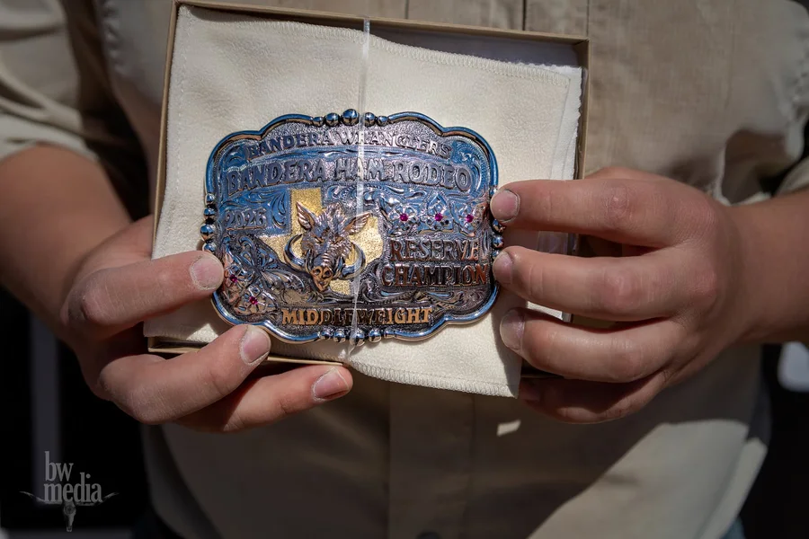 A winner holds a Ham Rodeo championship buckle in its gift box.