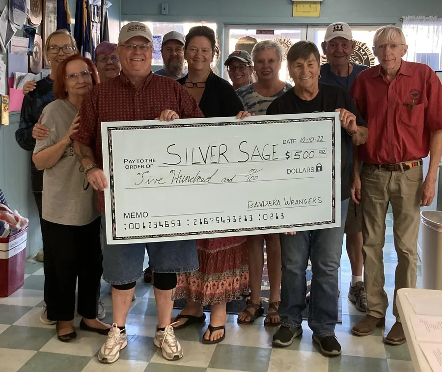 Wranglers members and friends holding a large five-hundred-dollar check made out to Silver Sage.
